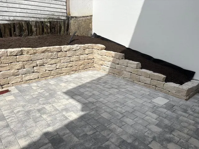 Gepflasterte Fläche mit neu gesetzter Natursteinmauer